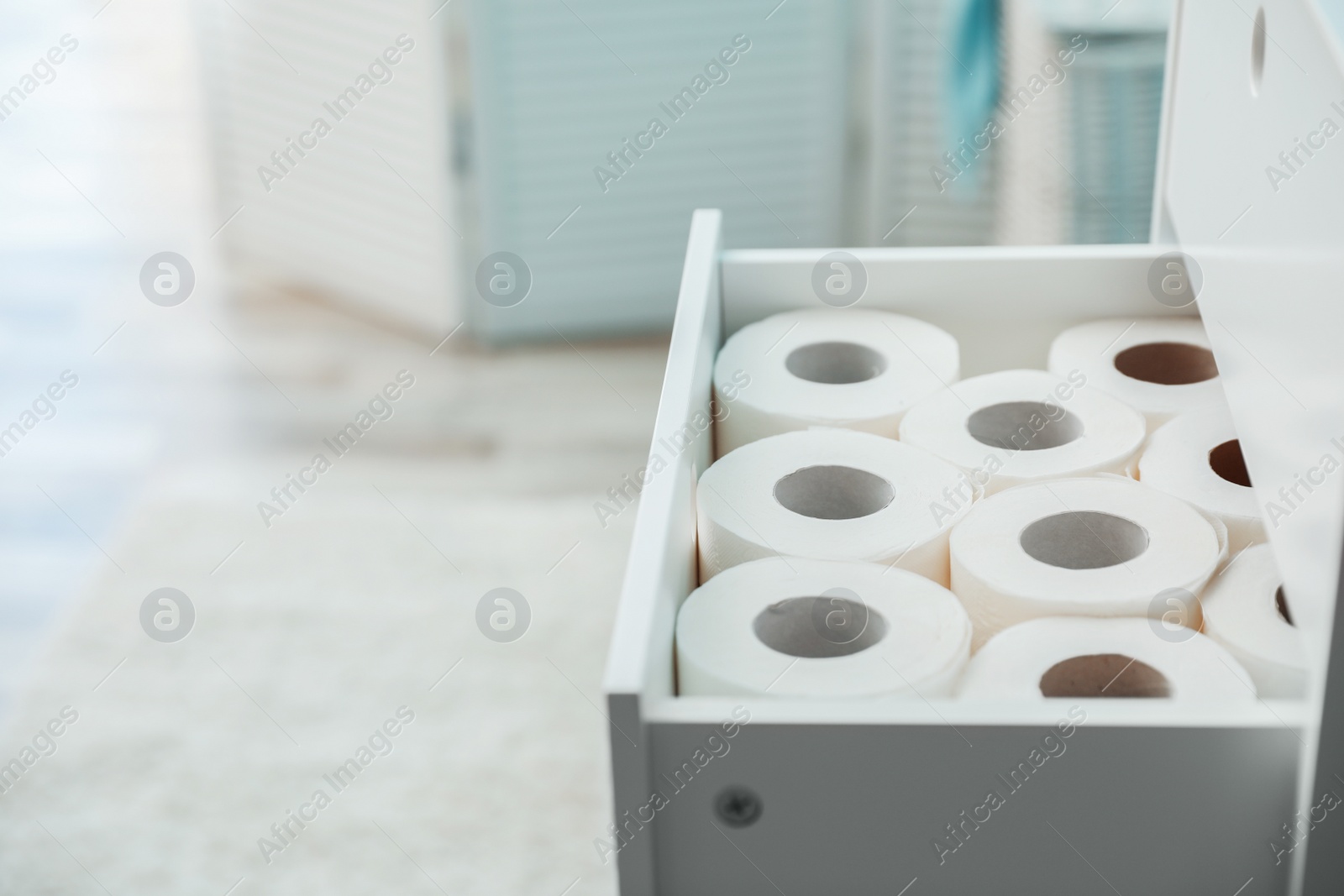 Photo of Open cabinet drawer with toilet paper rolls in bathroom. Space for text