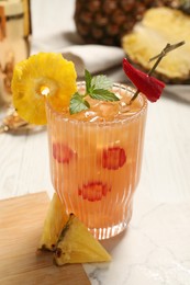 Photo of Glass of spicy pineapple cocktail with chili pepper and mint on white table