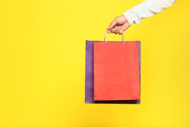 Photo of Young man with paper bags on color background, closeup