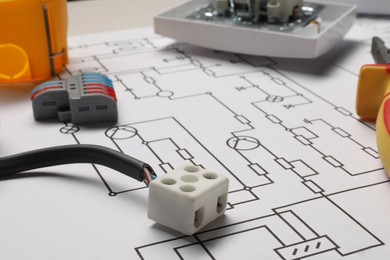 Wiring diagram and different electrician's equipment on table, closeup