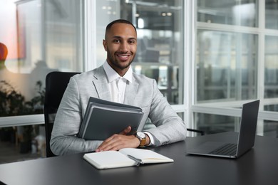 Photo of Happy man with folders working at table in office. Lawyer, businessman, accountant or manager