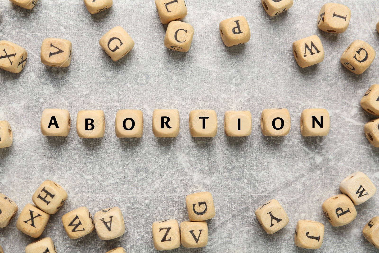 Photo of Word Abortion made of wooden cubes on grey background, flat lay