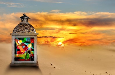 Image of Beautiful Arabic lantern on sand at sunset, space for text
