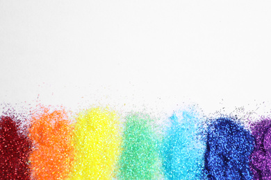 Photo of Bright glitters on white background, top view. Rainbow colors