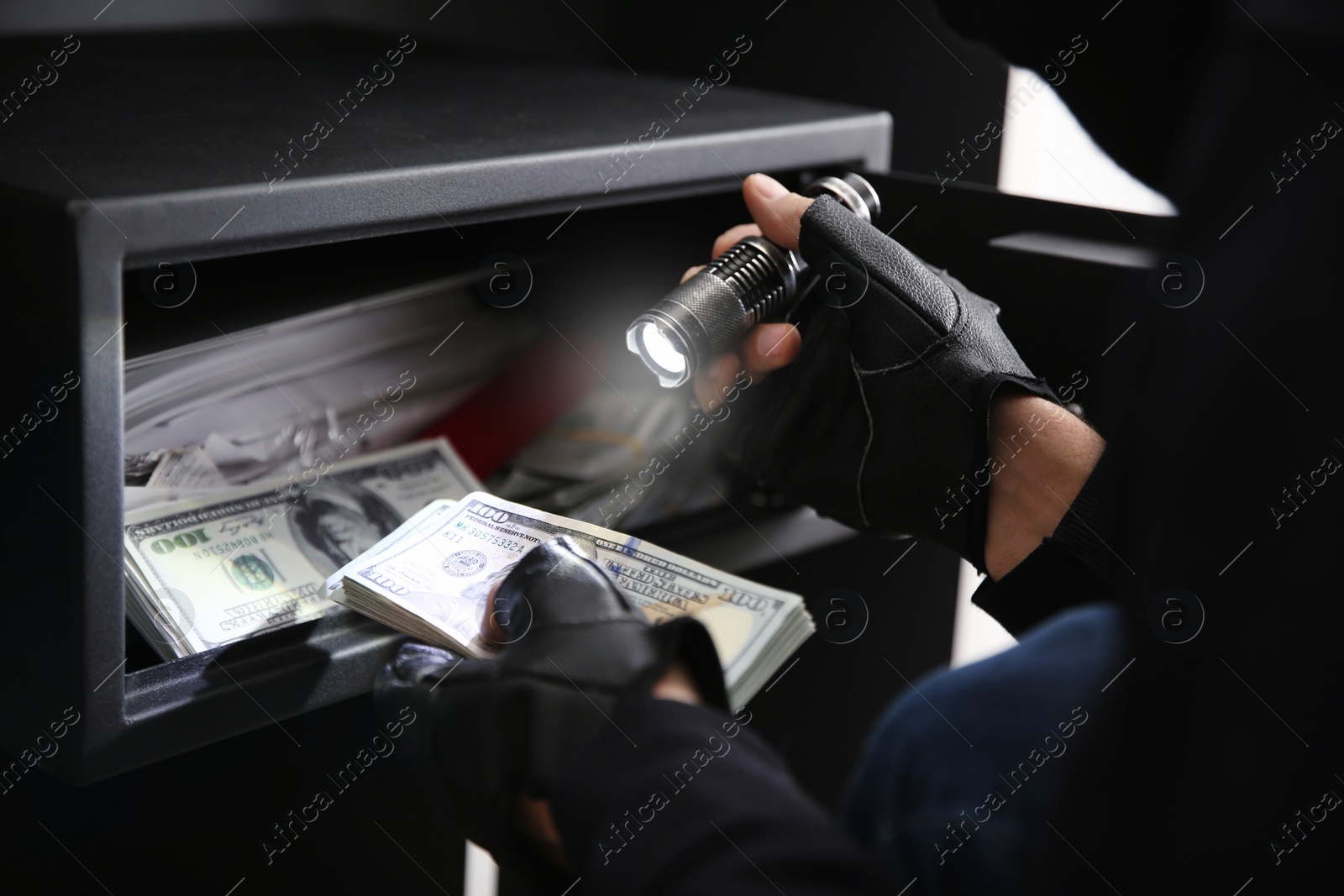 Photo of Thief taking money out of steel safe indoors, closeup