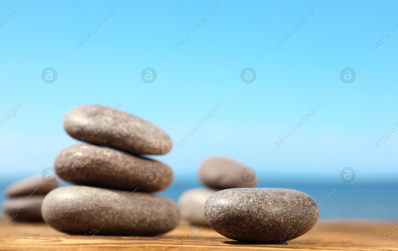 Photo of Stones on wooden table against seascape, space for text. Zen concept