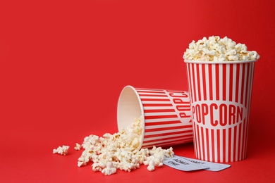 Popcorn and tickets on red background, space for text. Cinema snack