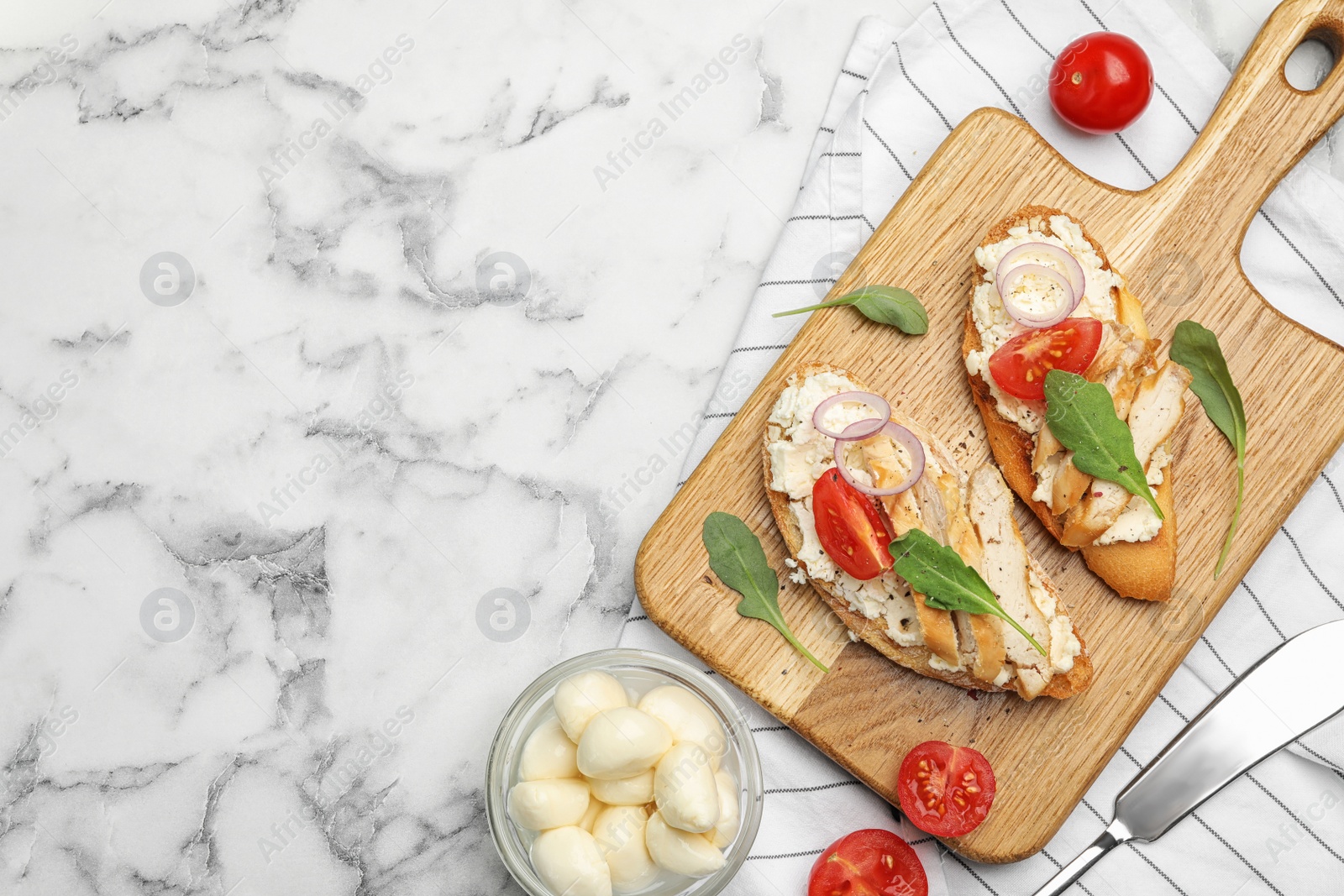 Photo of Board with delicious chicken bruschettas on white marble table, flat lay. Space for text