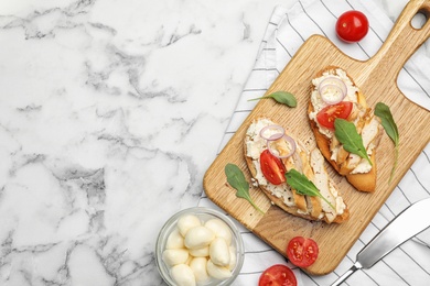 Board with delicious chicken bruschettas on white marble table, flat lay. Space for text