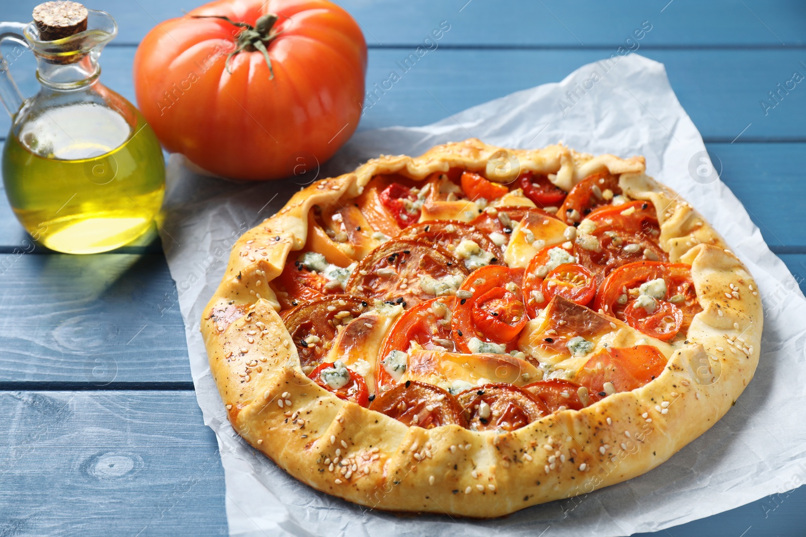 Photo of Tasty galette with tomato and cheese (Caprese galette) on blue wooden table, closeup