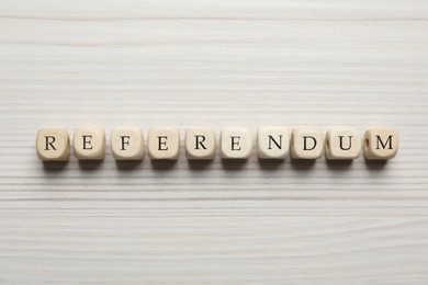 Word Referendum of cubes on white wooden table, flat lay