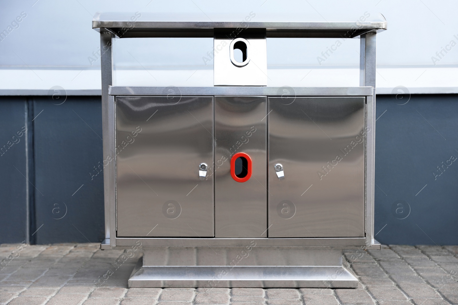 Photo of Modern metal recycling bin on street near building