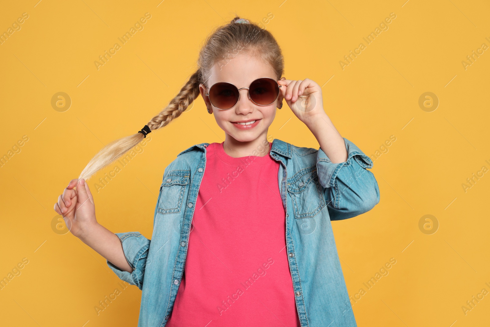 Photo of Girl in stylish sunglasses on orange background