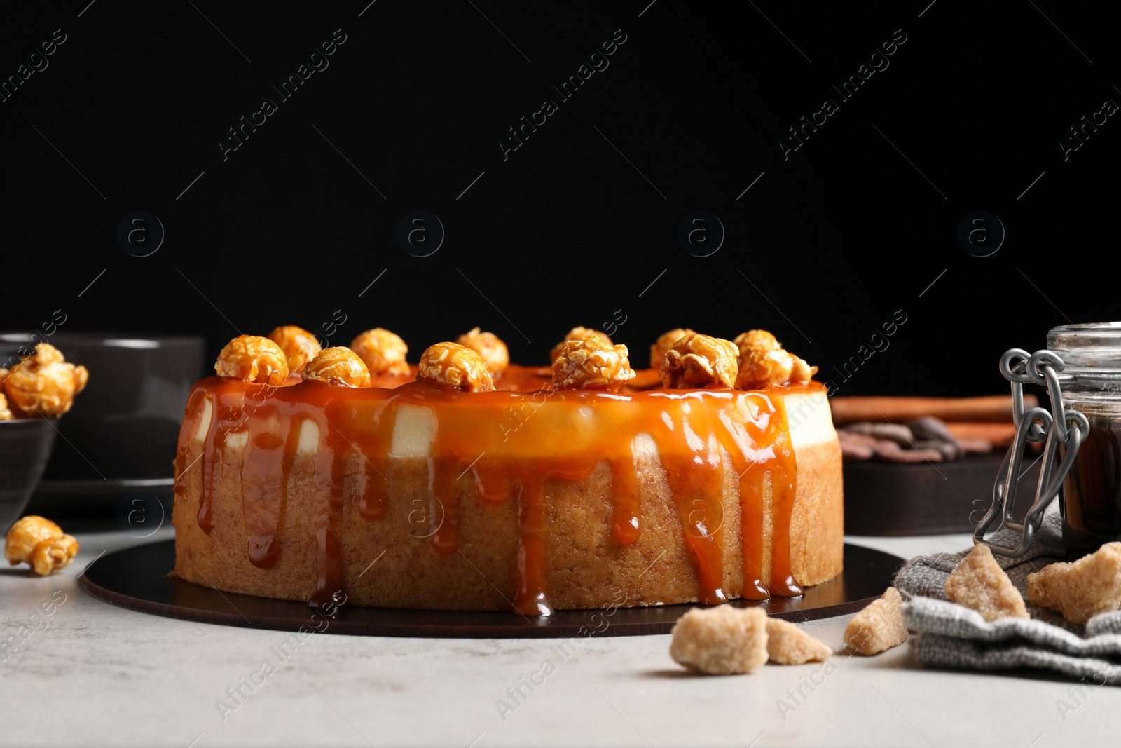 Photo of Sliced delicious cheesecake with caramel and popcorn on light grey table