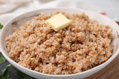 Tasty wheat porridge with butter in bowl on table, closeup