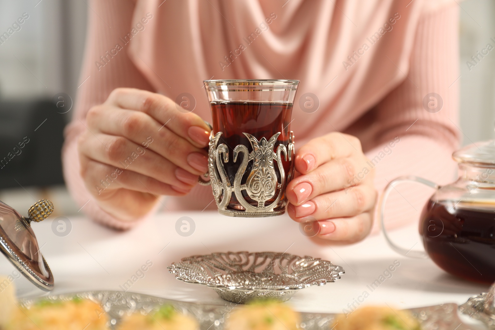 Photo of Woman with cup of delicious Turkish tea at white table, closeup