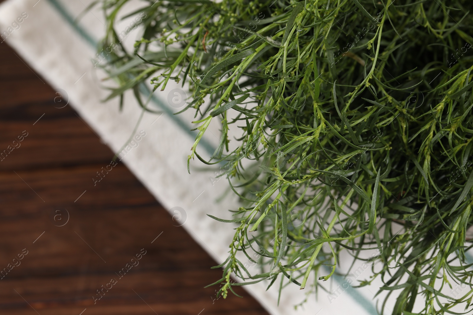 Photo of Colander with fresh tarragon leaves on wooden table, top view. Space for text