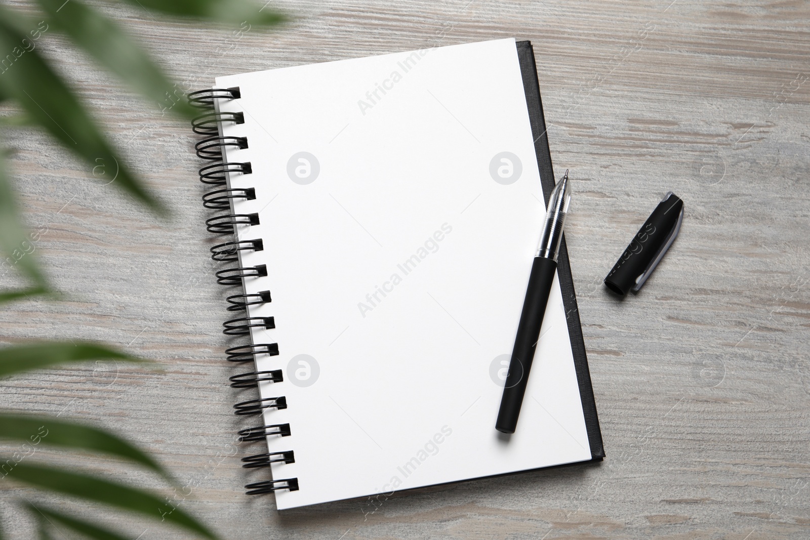 Photo of Open blank notebook and pen on light wooden table, flat lay