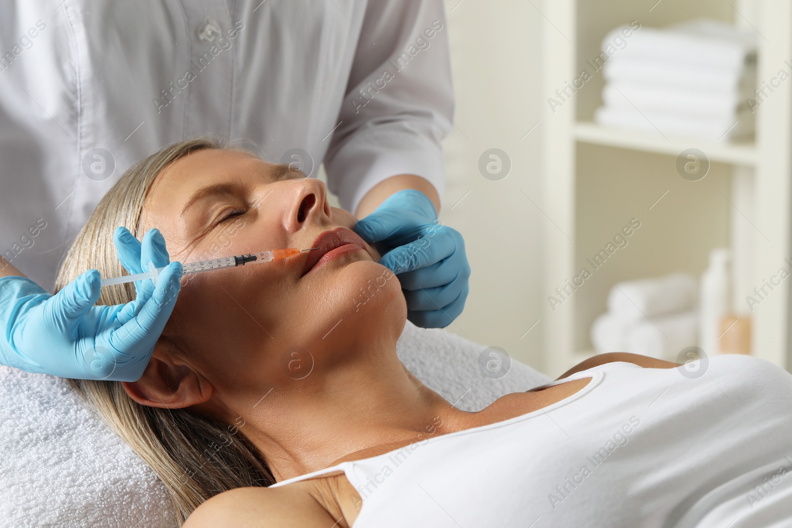 Photo of Doctor giving lips injection to senior woman in clinic. Cosmetic surgery