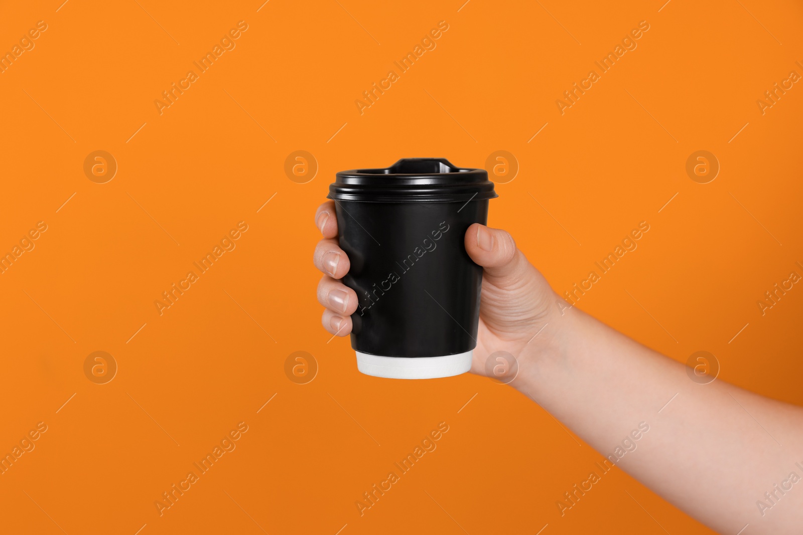 Photo of Woman holding takeaway cup with drink on orange background, closeup. Coffee to go