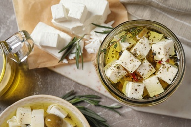 Flat lay composition with pickled feta cheese in jar on light brown table