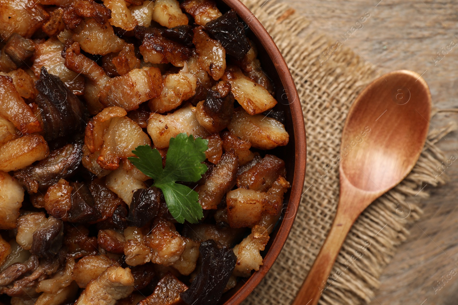 Photo of Tasty fried cracklings on wooden table, flat lay. Cooked pork lard