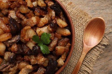 Photo of Tasty fried cracklings on wooden table, flat lay. Cooked pork lard