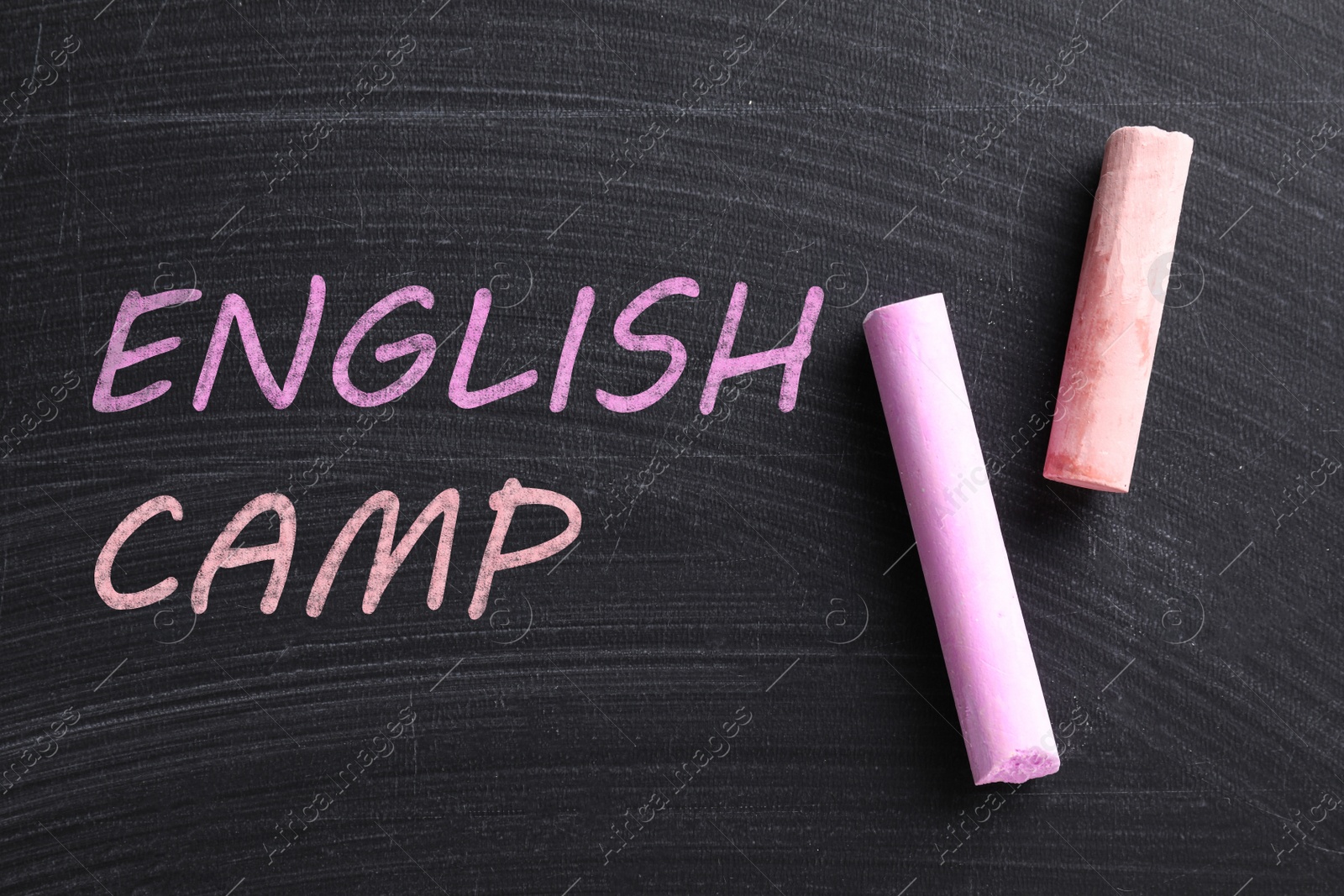 Image of Pieces of color chalk and words ENGLISH CAMP on blackboard, flat lay