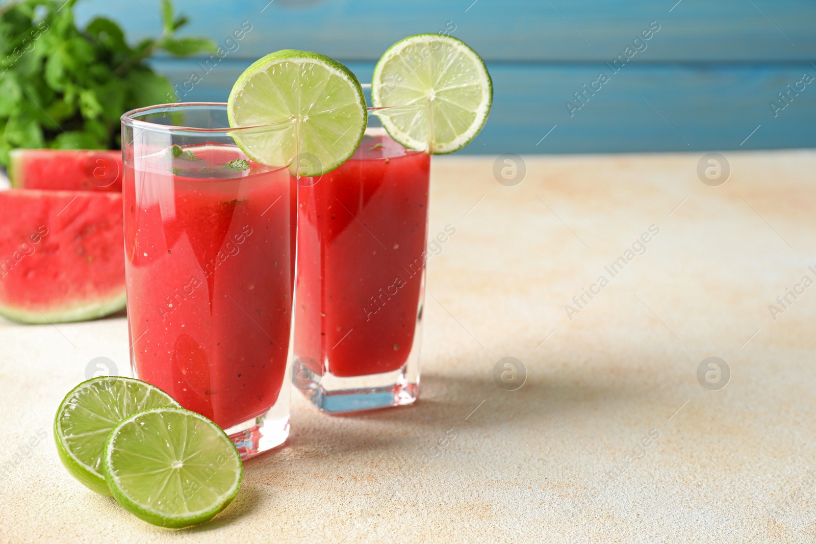 Photo of Tasty summer watermelon drink with lime in glasses on light table. Space for text