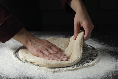 Woman kneading pizza dough at table, closeup