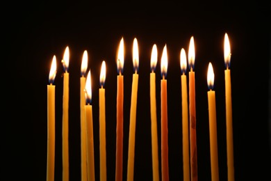 Many burning church candles on dark background