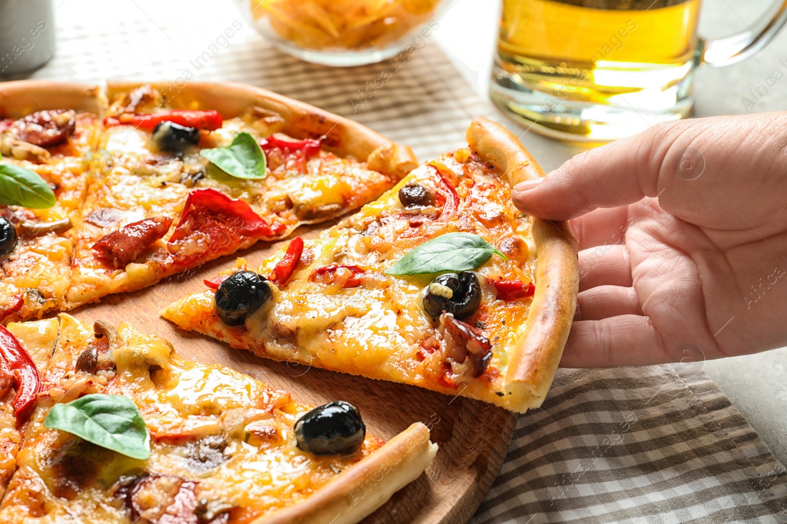 Photo of Woman taking slice of delicious pizza with olives and sausages at table
