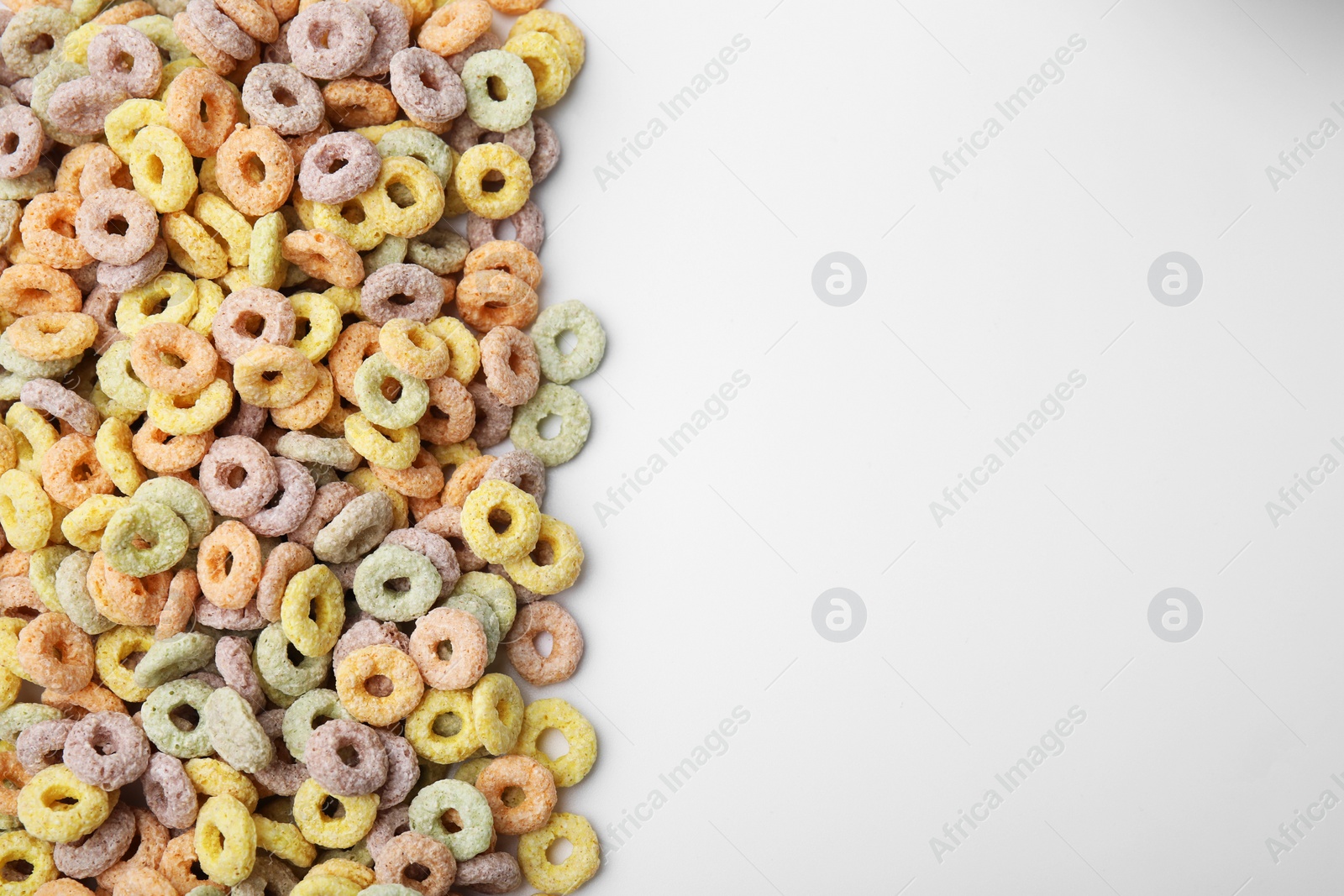 Photo of Tasty cereal rings on white background, flat lay. Space for text