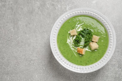 Photo of Tasty kale soup with croutons on grey table, top view. Space for text