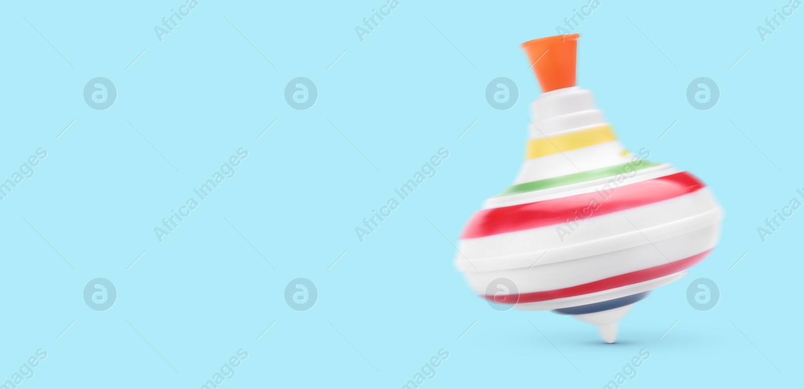 Image of One spinning top in motion on light blue background, banner design with space for text. Toy whirligig