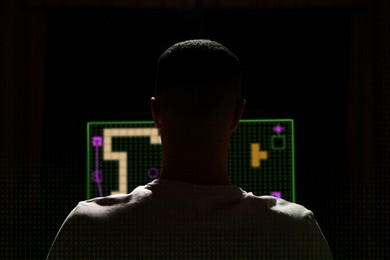 Image of Gaming disorder. Man playing on computer in darkness, back view