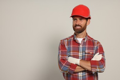 Photo of Professional builder in hard hat on light background, space for text