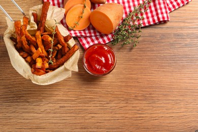 Photo of Sweet potato fries, thyme and ketchup on wooden table, flat lay. Space for text