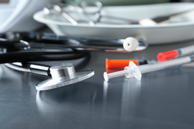 Photo of Stethoscope and syringes on grey table. Medical objects