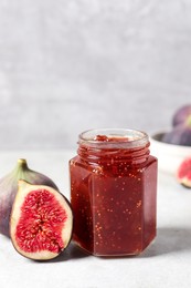Photo of Jar of tasty sweet jam and fresh figs on white table