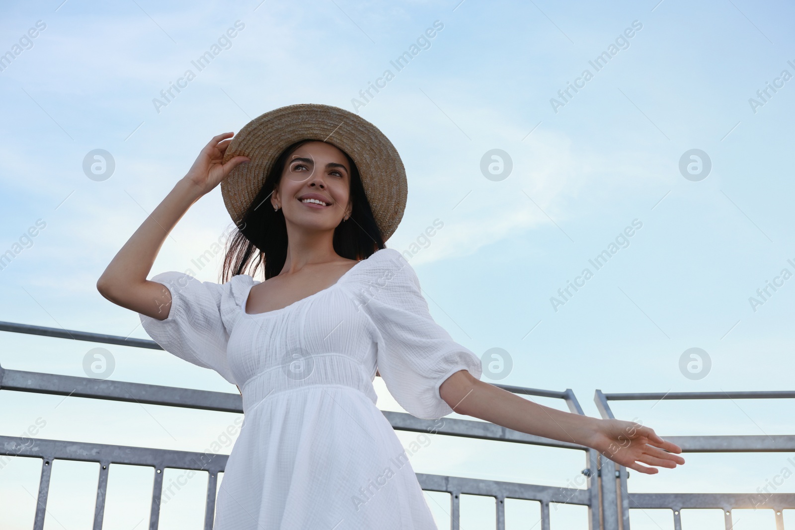 Photo of Happy woman enjoying feeling of freedom near metal railing outdoors, low angle view