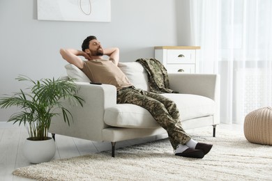Soldier napping on soft sofa in living room. Military service