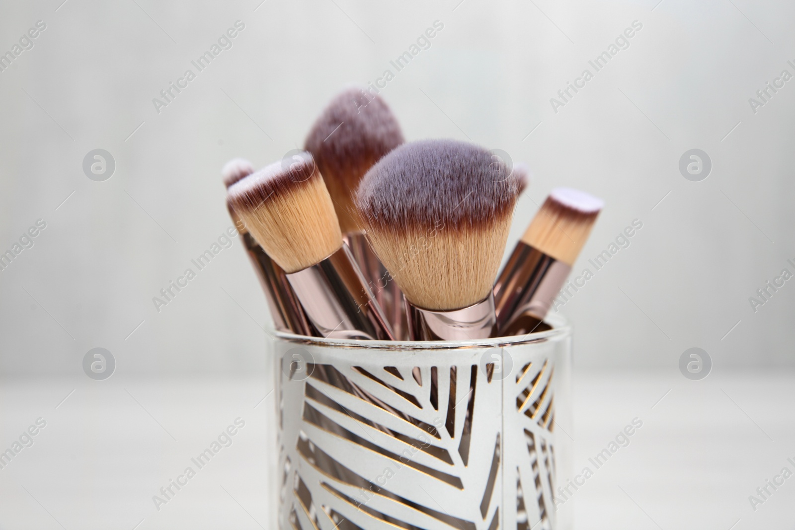 Photo of Organizer with professional makeup brushes against light background, closeup