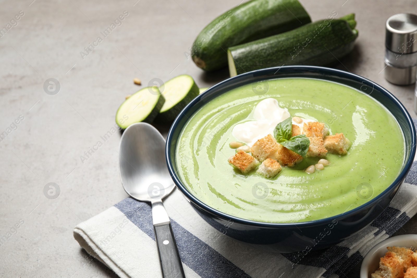 Photo of Tasty homemade zucchini cream soup served on grey table