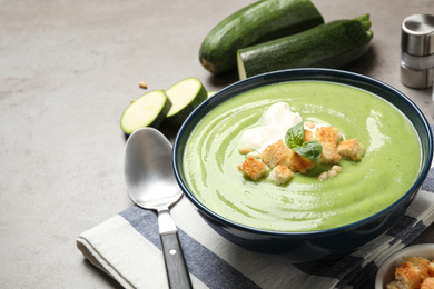 Tasty homemade zucchini cream soup served on grey table