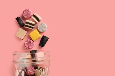 Photo of Jar with tasty liquorice candies on pink background, top view. Space for text