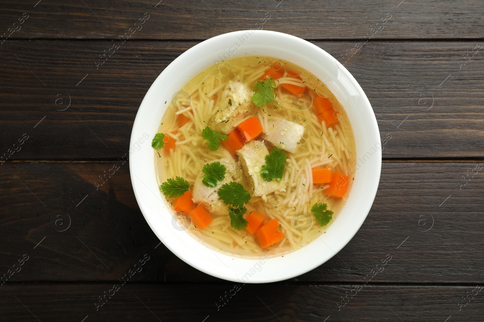 Photo of Dish with fresh homemade chicken soup on wooden background, top view