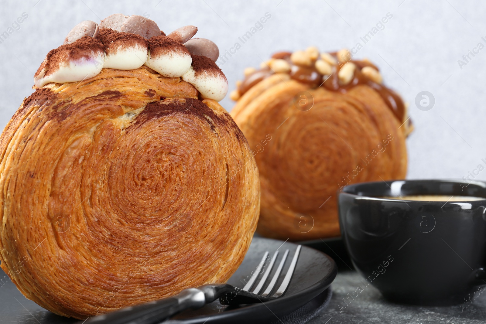 Photo of Tasty puff pastry. Round croissants served with coffee on grey table, closeup