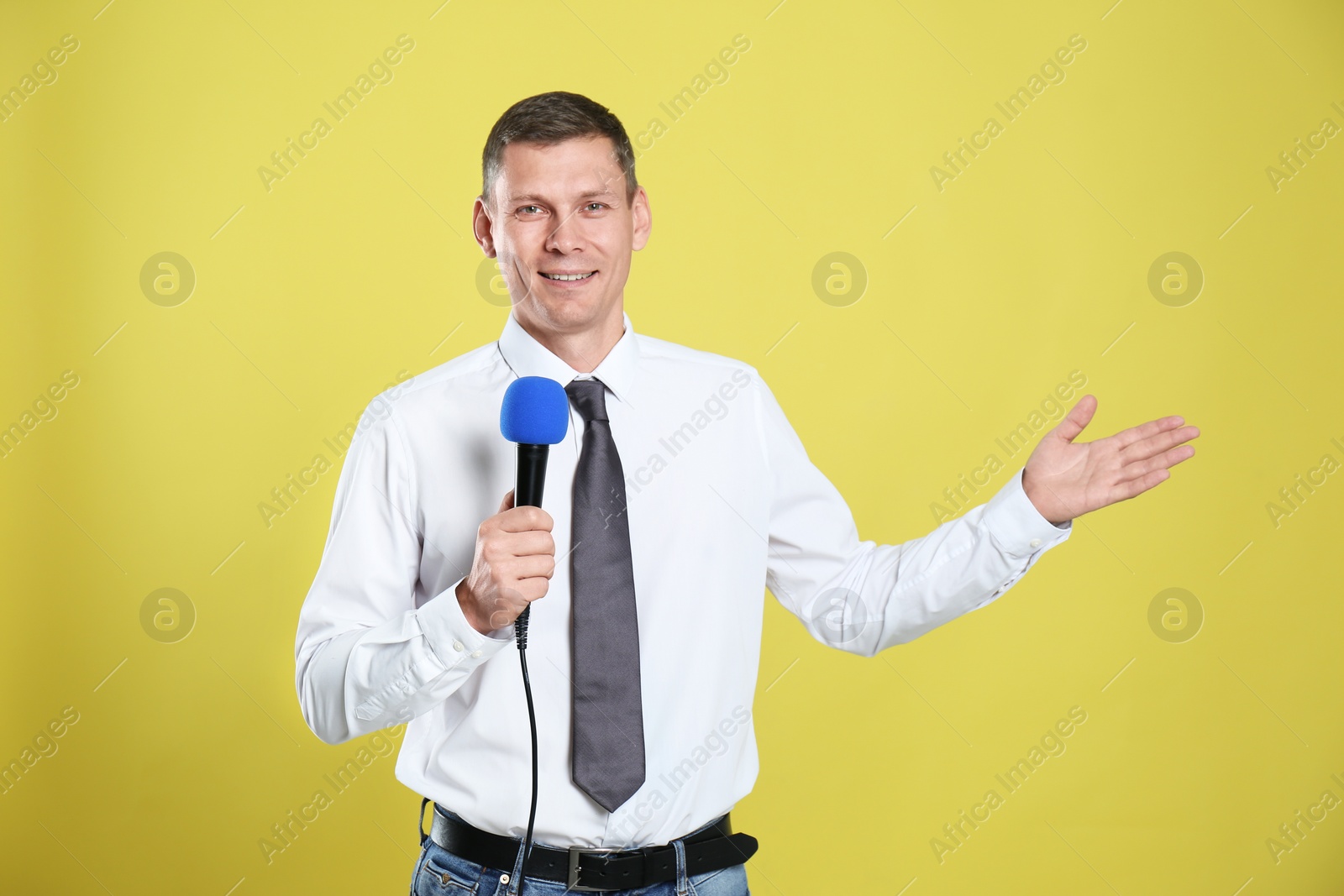 Photo of Male journalist with microphone on yellow background