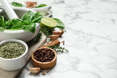 Photo of Different natural spices and herbs on white marble table. Space for text